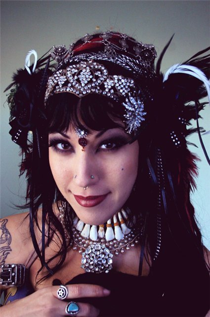 Close-up portrait of Sharon Kihara in a feathered, jeweled headdress and a shell and bead necklace