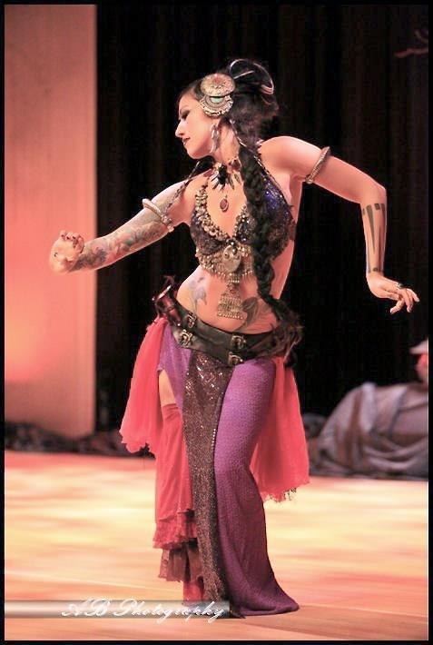 Sharon Kihara dancing on stage in an embellished costume with a flowing pink skirt