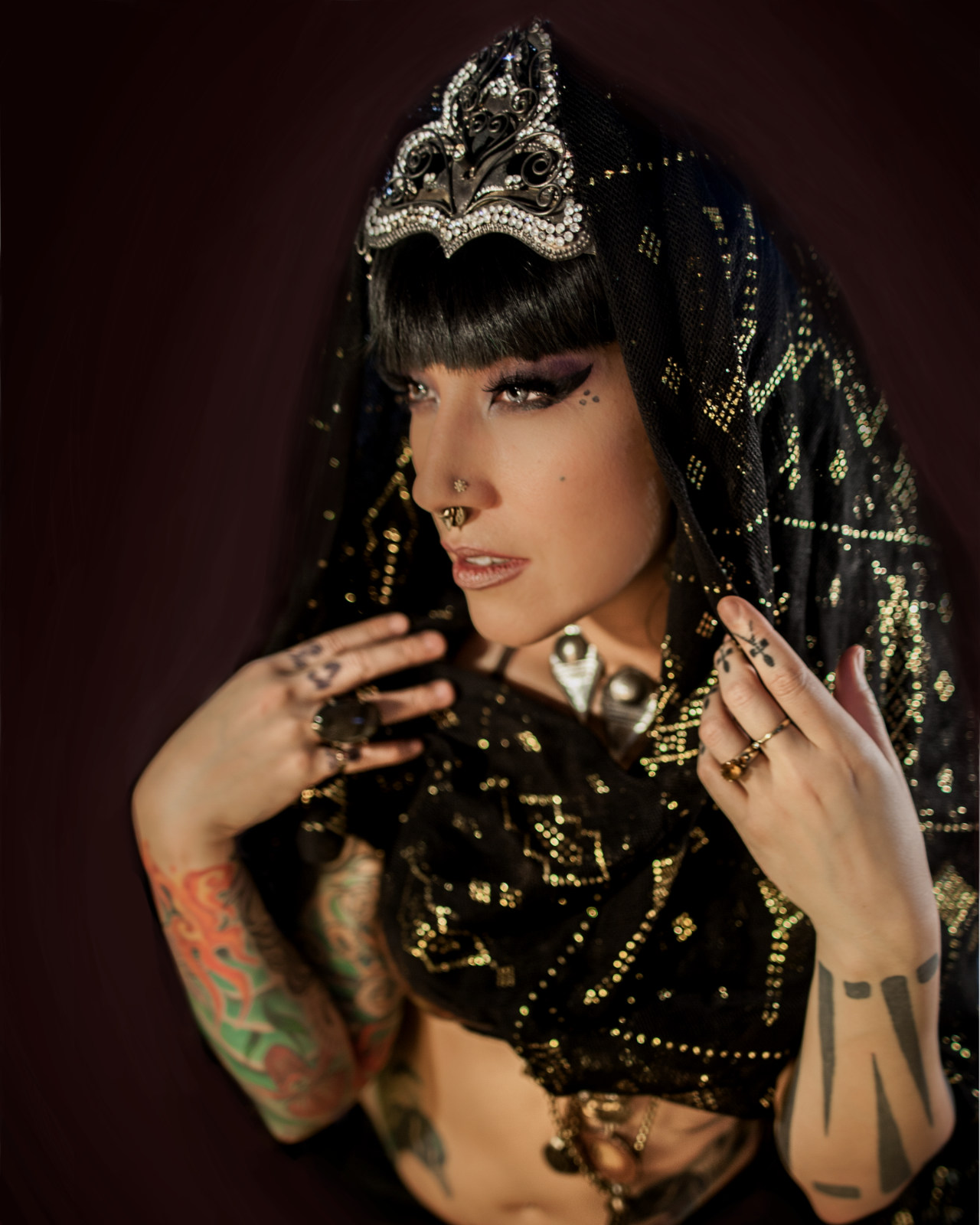 Close portrait of Sharon Kihara in a beaded black veil and a jeweled crown, hands raised to her chest